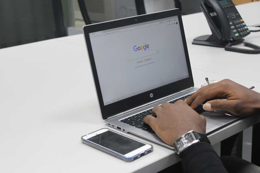 Google search screen of laptop with user hands on keyboard
