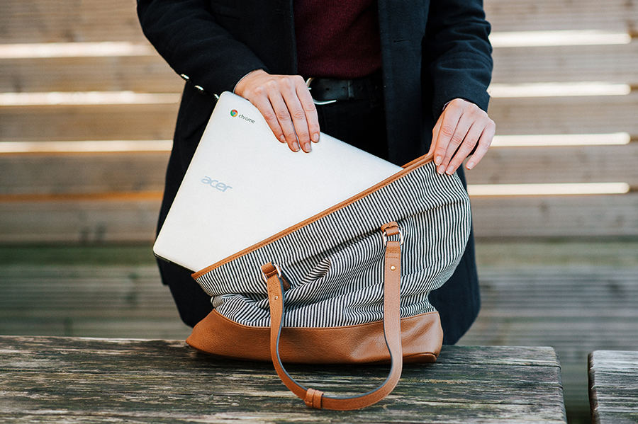 Close up of woman's hands putting chromebook laptop in bag