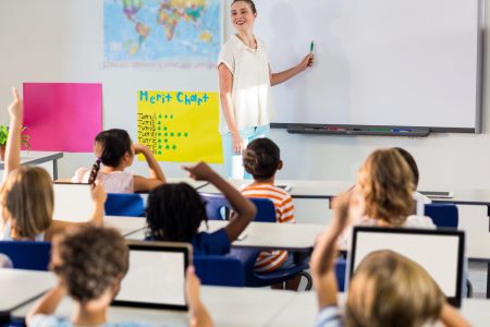 Teacher in classroom speaking to student out of focus.