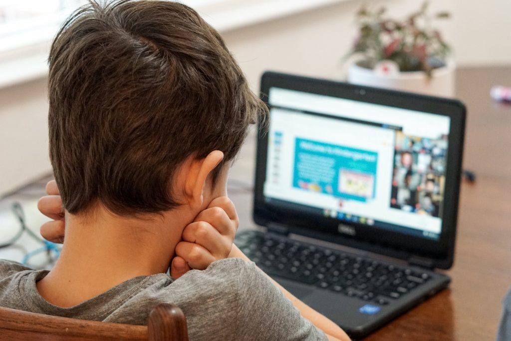 Young boy in home setting in front of laptop during remote learning instruction